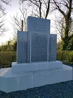 Vue d'un monument en granit sur une base en béton présentant une liste