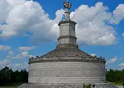Monument ressemblant à un mausolée surmonté par une gigantesque statue, construction moderne.