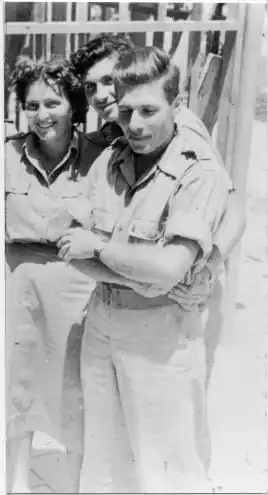 Une femme et deux hommes en uniforme souriants, Kelman tête baissée. Noir et blanc.