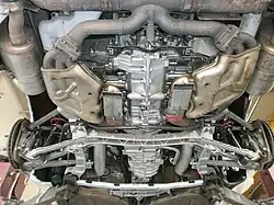 Vue par le dessous du train arrière LSA. On voit au premier plan le carter ainsi que les échappements du moteur. Le train arrière est légèrement en retrait du moteur et sous la boîte de vitesses.