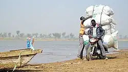 Moto transportant des marchandises sur la rive du fleuve Logone