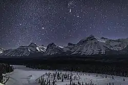Sous une nuit brillamment étoilée un paysage de neige avec une belle vallée et de grandes montagnes.