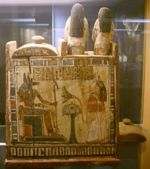 photographie d'un coffret décoré par une image d'Anubis assis sur un trône.