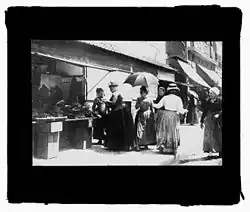 Étal de marchande de légumes devant le no&nbsp;16 (photographie sur verre de Georges Ancely, 1894).