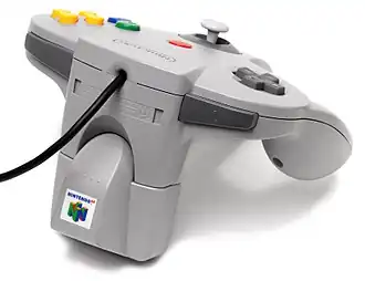 Accessoire électronique encastré sous une manette de Nintendo 64.
