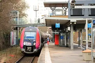 Cliché en couleur. Une rame automotrice se trouve à quai ; des voyageurs y montent.
