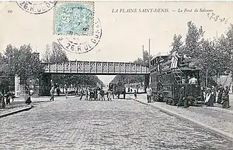 Tramway à impériale sous le pont de Soissons (à proximité de l'ancienne gare de La Plaine-Voyageurs), avenue du Président-Wilson (RN1, au tout début du XXe&nbsp;siècle.