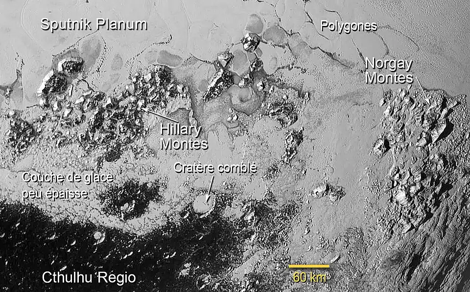 Partie sud de Sputnik Planum sur Pluton : des glaces exotiques s'écoulent entre les massifs Hillary et Norgay et en comblant notamment le grand cratère annoté de 50&nbsp;km de diamètre.