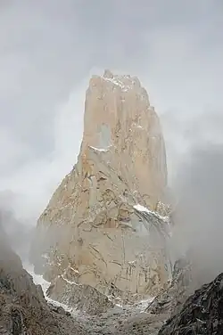 Pic montagneux, entouré par une vague de brume, saupoudré de neige