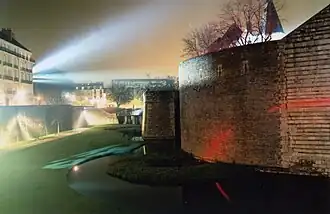 Photographie du château éclairé la nuit.