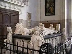 Un tombeau de marbre blanc richement sculpté, avec deux gisants.