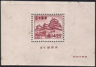 Photo couleur d'un Bloc-feuillet de couleur chair présentant, en son centre, un timbre aux teintes framboise figurant un château fort.