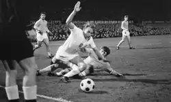 Scène d'un match de football. Un joueur en tacle un autre près de la ligne de touche.