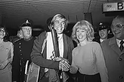 Photographie en noir et blanc d'un homme entouré par la foule et félicité par une femme.