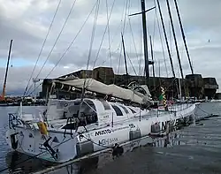 Voilier blanc, amarré au ponton, vu de trois quarts arrière.