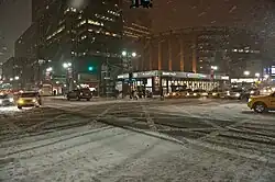 Rue de New York remplie de neige, photographiée dans la nuit.