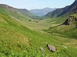 Outdoor countryside scene, with fells on either side of lush green valley