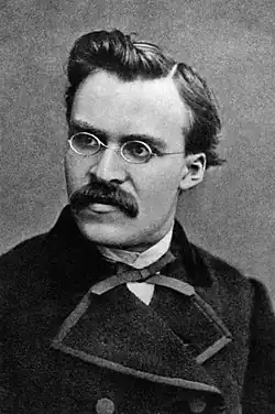 Buste d'homme. Sur fond neutre, le visage et le regard sont tournés vers la gauche, donnant du mouvement au portrait. Le personnage moustachu porte de fines lunettes rondes, un nœud papillon fin et un manteau noir fermé