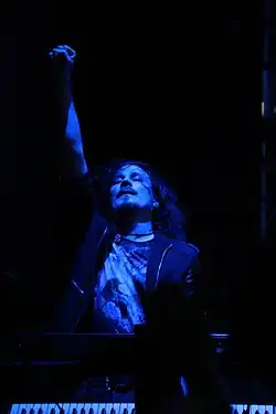 Image d'un homme au cheveux longs jouant du clavier et éclairée de bleu