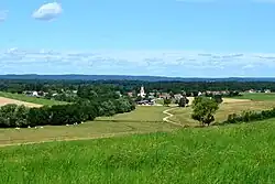 Photographie en couleurs de la rue principale d'un village et d'un lotissement.