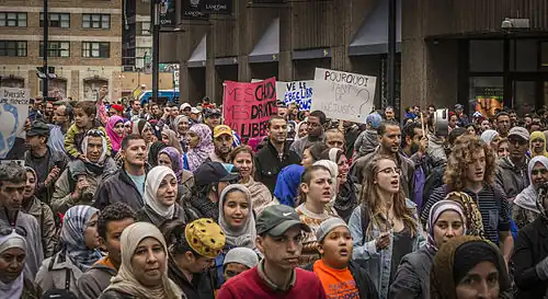 Image présentant plusieurs personnes défilant dans une rue de Montréal, certaines avec des pancartes