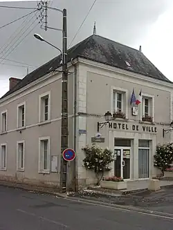 Photographie en couleurs d'un bâtiment portant l'inscription « HOTEL DE VILLE» en façade et décoré de drapeaux.