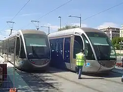Image représentant les essais sur le boulevard Jean-Jaurès avec deux tramways à l'arrêt et un homme en gilet jaune traversant la voie du tramway.