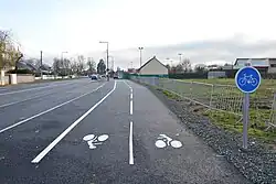 Piste cyclable avec, en arrière-plan, la route départementale