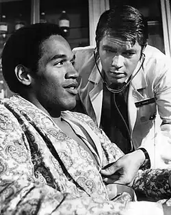 Image en noir et blanc d'un médecin auscultant un homme assis en peignoir.