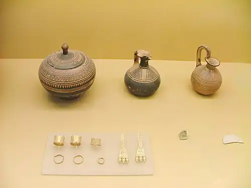 De g. à d., pyxis globulaire, œnochoé-lécythe, aryballe. Pendants d'oreille et bagues. Tombe d'une femme enceinte riche. Vers 850.Musée de l'ancien Agora
