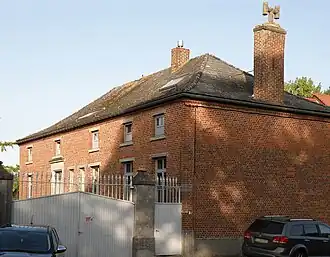 Portail d’entrée de la ferme rue Général Cochez no&nbsp;35. À droite, forte bâtisse néo-classique.