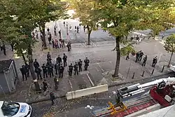 Des opposants à la rénovation de la place Jean-Jaurès de Marseille manifestent pacifiquement devant un groupe de CRS, pendant qu'un muret de béton est installé.