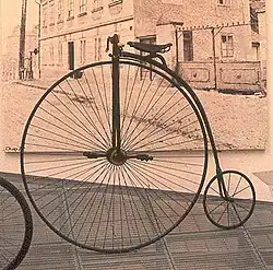 Énorme roue avant avec pédalier et selle, et petite roue arrière