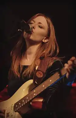 Orla Gartland en train de chanter sur scène avec sa guitare.