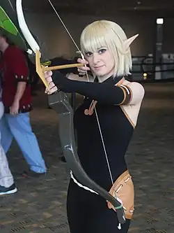 Cosplay d'Evangelyne, en habit moulant noir, cheveux blonds et oreilles pointues.