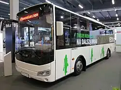 Photographie en couleurs d’un autobus blanc exposé sur un salon.