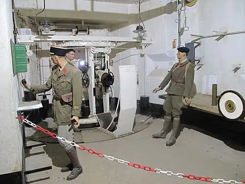 Un des lance-bombes de 135&nbsp;mm ; le bloc 2 est le seul de la ligne a en avoir deux. Ils lancent des obus de 17 à 19&nbsp;kg, capable de détruire les constructions et retranchements. Les contrepoids permettent d'équilibrer la pièce, les volants servent au pointage en direction et en hauteur.