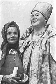 Photographie ou dessin en nuances de gris montrant une vieille femme portant un fichu aux côtés d'une femme plus grande, richement vêtue.