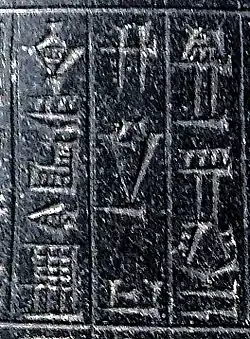 Signes cunéiformes gravés sur une pierre noire.