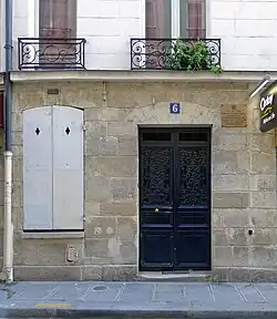photo d'une façade avec porte d'entrée numérotée 6 et fenêtre aux volets fermés