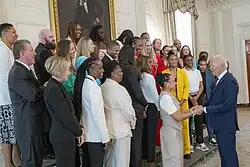 Joueuses en tenue officielle, sur 3 rangs, face à un homme