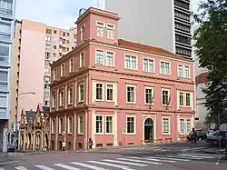 Bâtiment du dix-neuvième siècle de couleur rose à l'intersection de deux rues dans une grande ville.