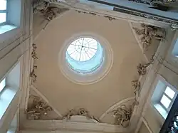 Un plafond avec un lanternon et des sculptures autour.