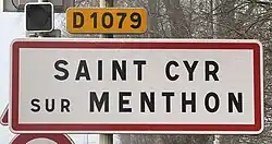 Panneau blanc avec un liseré rouge où il est inscrit "Saint-Cyr-sur-Menthon" en son centre en lettres noires. Ce panneau est surmonté d'un panonceau jaune où il est inscrit "D 1079".