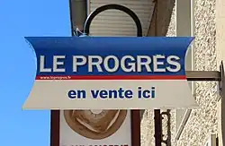 Panneau de commerce à la boulangerie du bourg annonçant la vente du journal de Le Progrès.