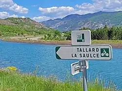 Photo montrant deux panneaux indicateurs avec en arrière-plan un canal et la montagne.