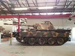 Photographie prise dans un musée montrant un char Panther vu de profil ; il est peint en couleur camouflage et porte le numéro II01 en rouge sur la tourelle.