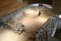 Vue de ruines d'une pièce semi-circulaire avec une construction à l'intérieur.