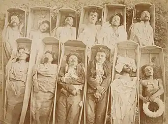 Photographie montrant douze cadavres dans des cercueils en bois.