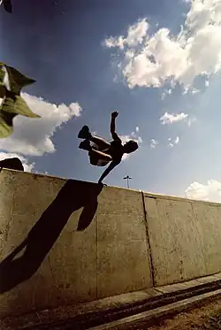 Un pratiquant de parkour au cours d'un saut « passement rapide » au-dessus d'un muret